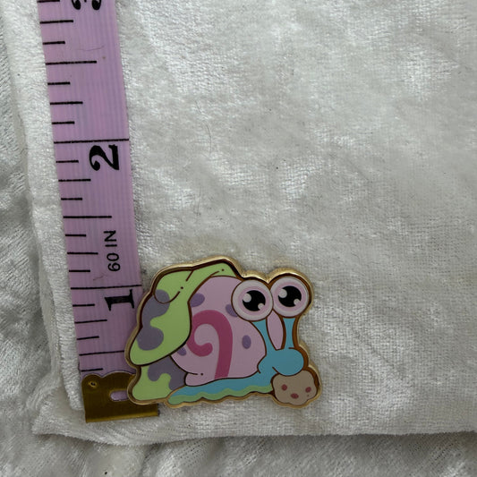 Gary enamel pin by Xhilyn next to a ruler showing its height of 1.86 inches.