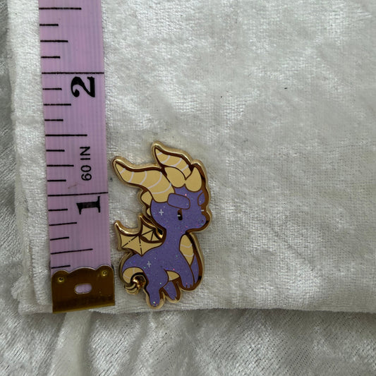 Spyro the Dragon enamel pin by Xhilyn placed next to a tape measure showing its exact 1.5-inch height.