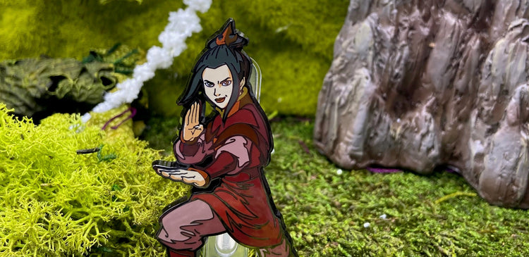 This image features an awesome, officially licensed Azula FiGPiN collectible pin from Avatar: The Last Airbender. Azula is shown in her iconic dark red Fire Nation attire, with her sharp topknot and a determined, intense expression.