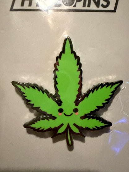 Close-up of the 'Cute Weed Leaf' hard enamel pin, showcasing its glossy finish, crisp black outline, and vibrant green details.