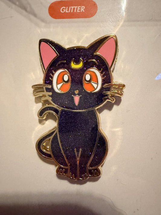 Close-up of the **Sailor Moon Cat Luna Hard Enamel Pin**, highlighting its wise expression, sleek hard enamel finish, and luxurious **gold plating**. A detailed anime collectible by Hype Pins.