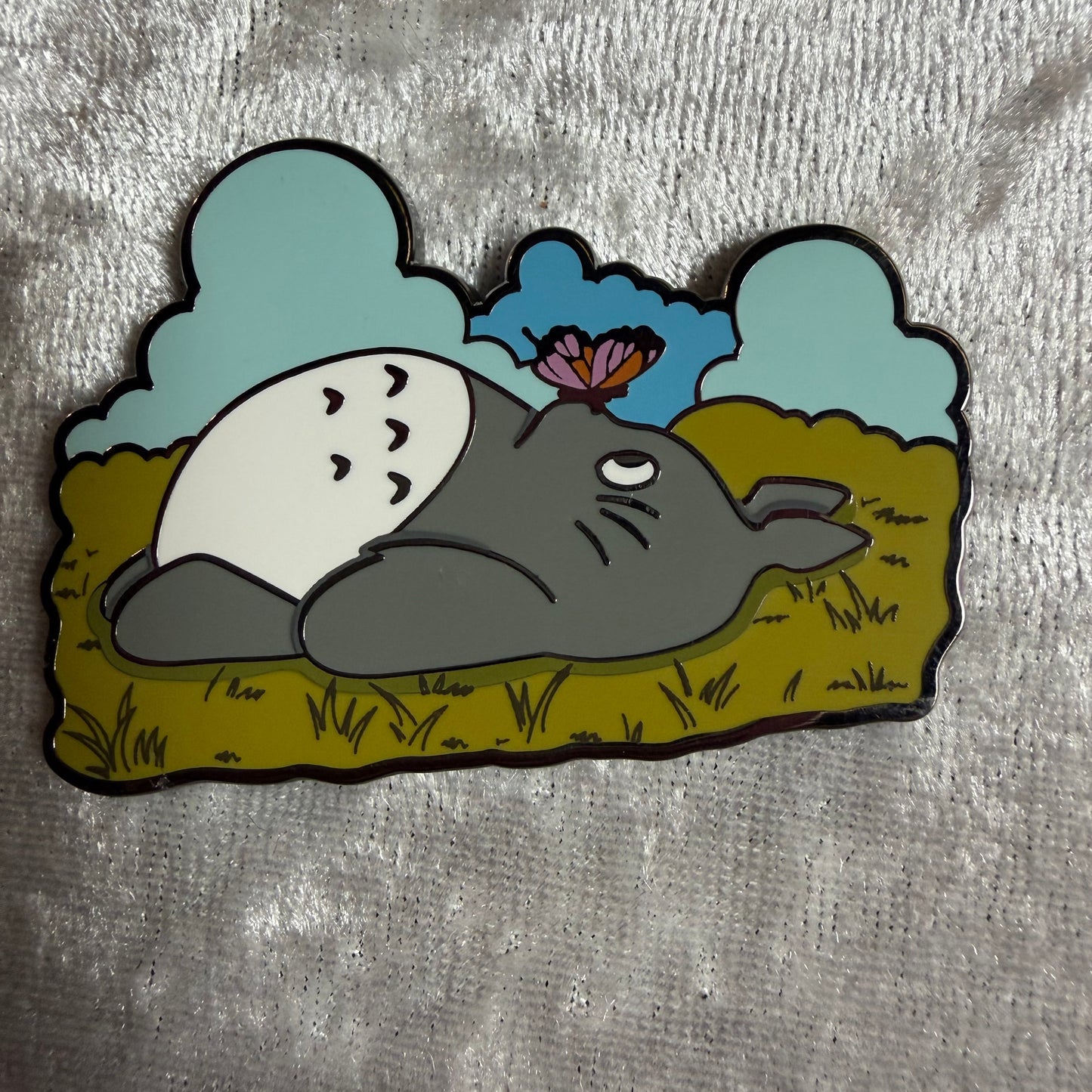 Close-up of the screen-printed details and gold plating on the Totoro spring collectible enamel pin.