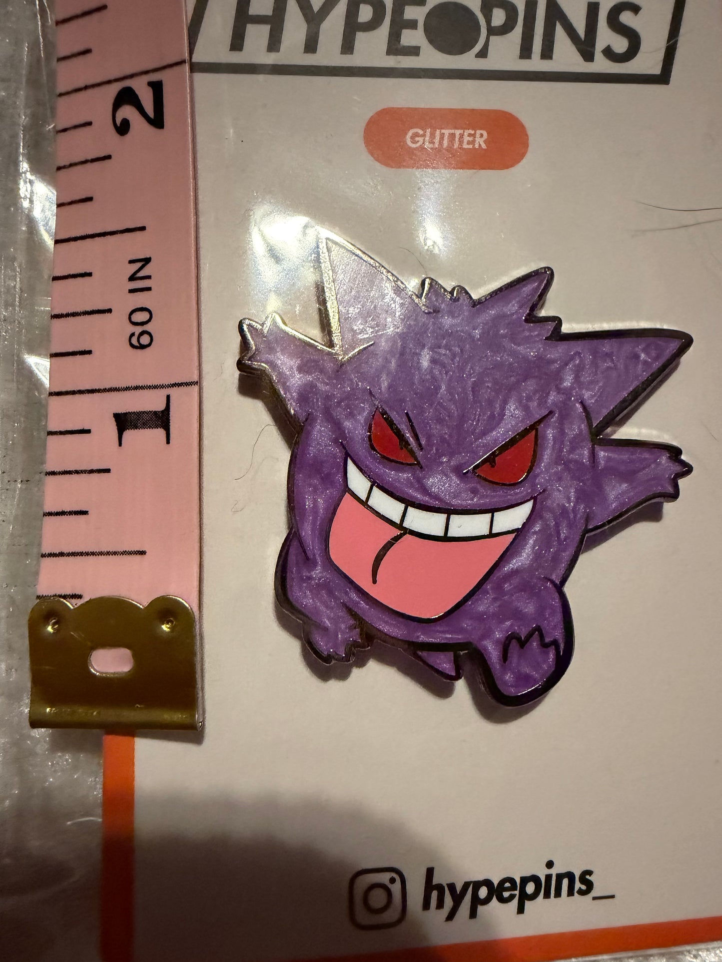 Gengar Hard Enamel Pin by Hype Pins, displayed next to a tape measure to show its **1.5-inch size**. This Pokémon collectible features **pearl accents** and a black nickel metal finish.