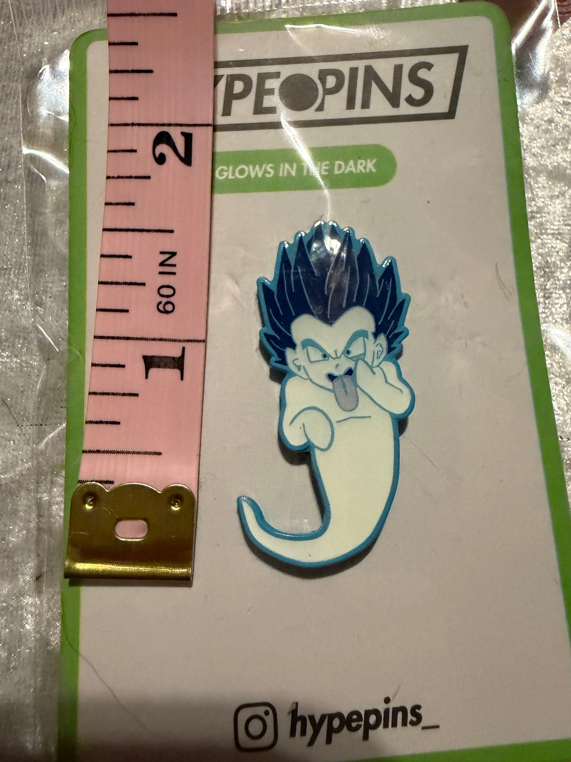 Gotenks Ghost Bomb Dragon Ball Z Enamel Pin next to a tape measure, showing its 1.25-inch size and black nickel metal detail. This collectible also **glows in the dark**.