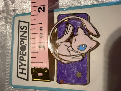 Mew Galaxy Spinning Pokémon Enamel Pin by Hype Pins, positioned next to a tape measure to illustrate its **1.75-inch size**. Highlights its gold plating and spinning feature.