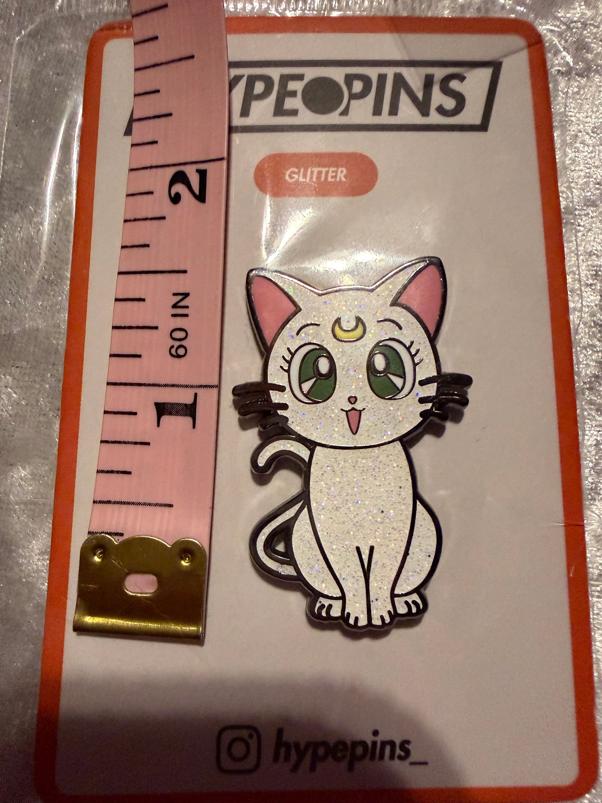 Sailor Moon Cat Artemis Hard Enamel Pin by Hype Pins, displayed next to a tape measure to show its **1.5-inch size**. This iconic anime collectible features a durable hard enamel finish.
