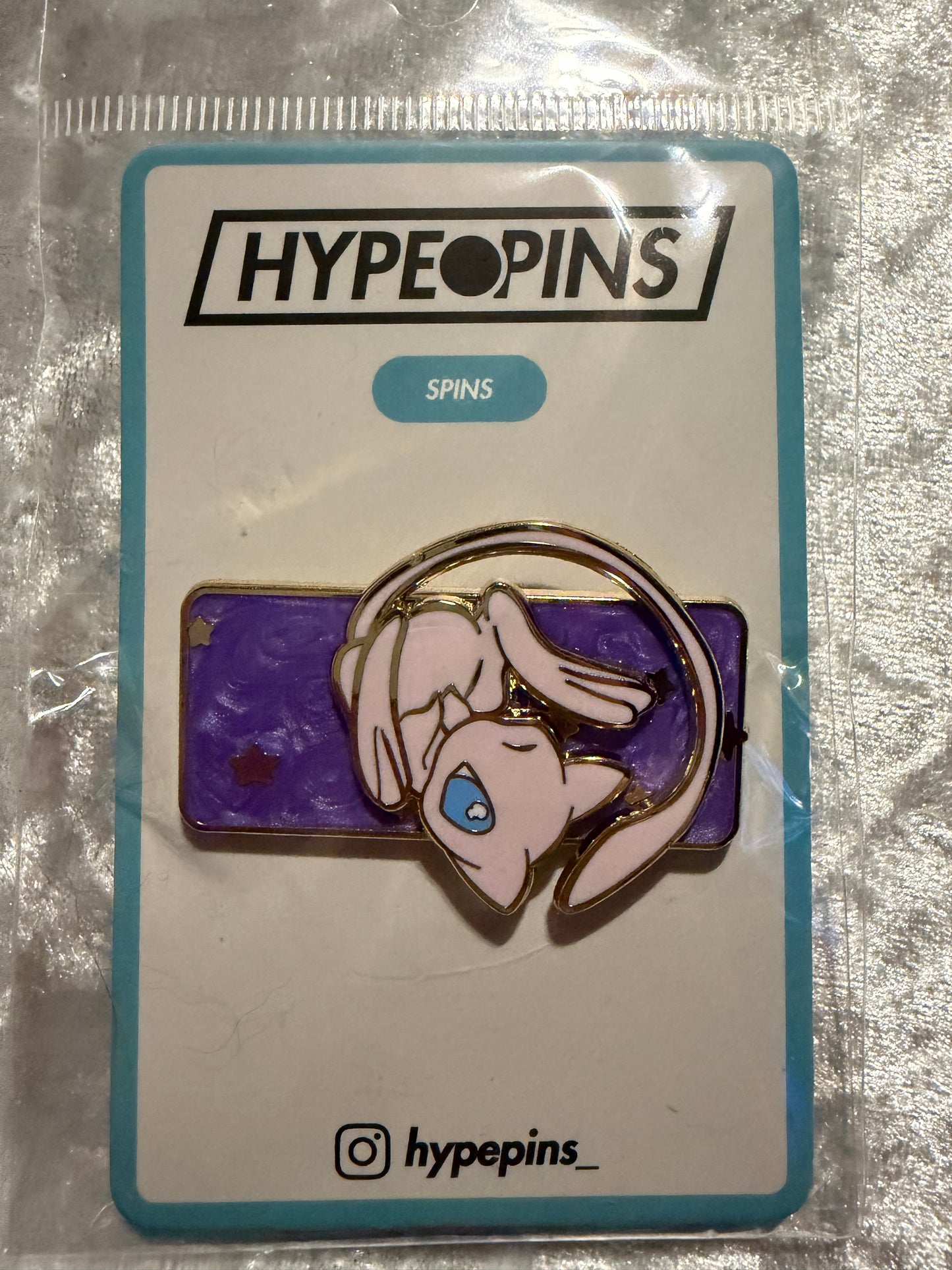The **Mew Galaxy Spinning Hard Enamel Pin**, a beautiful and interactive **Pokémon collectible** featuring Mew within a glittering, gold-plated galaxy design.