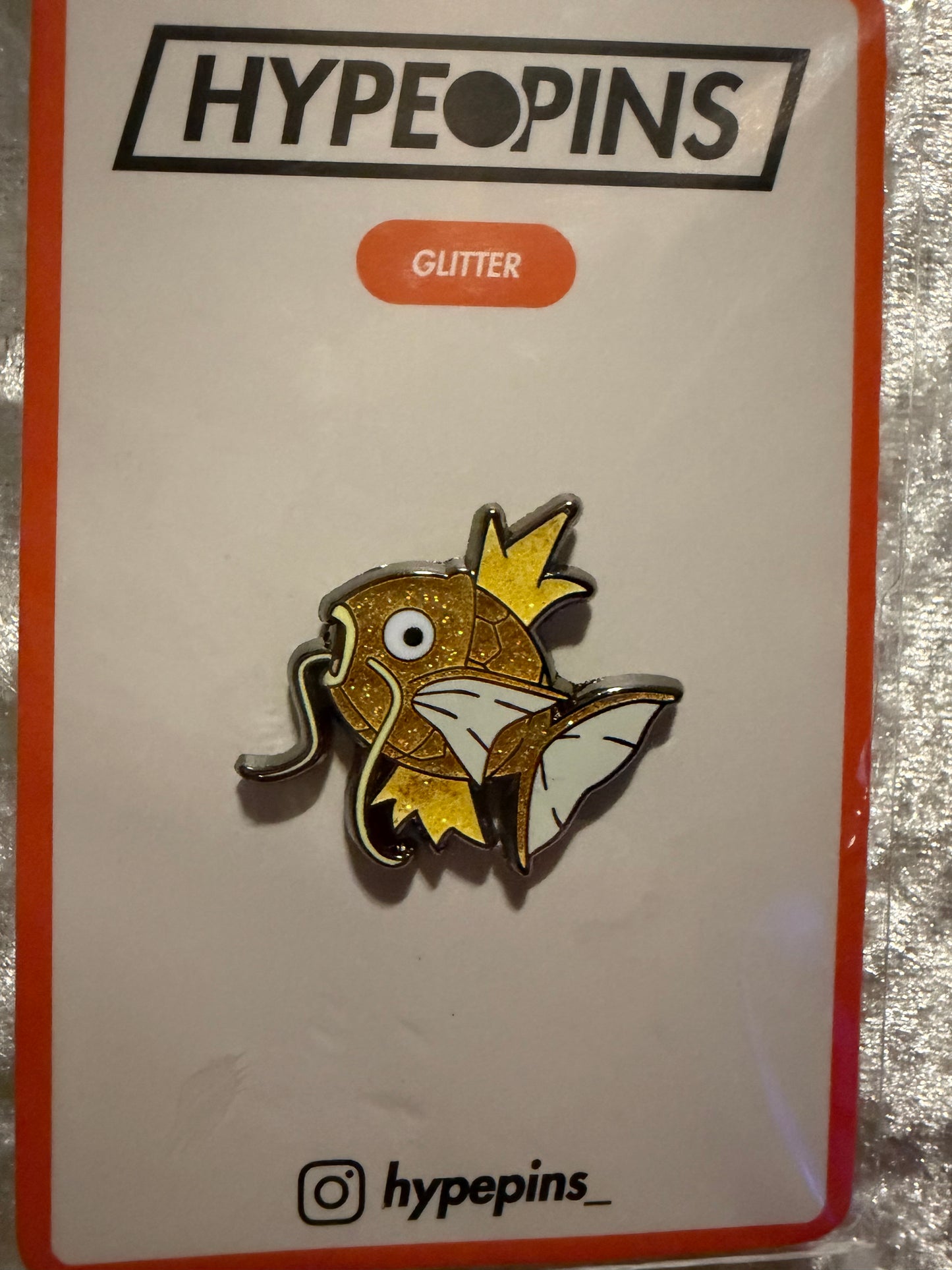 The **Shiny Magikarp Hard Enamel Pin**, a compact and eye-catching **Pokémon collectible** featuring the rare golden Magikarp, perfect for any fan's collection.