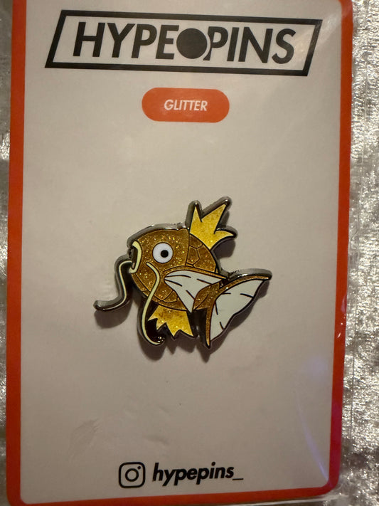 The **Shiny Magikarp Hard Enamel Pin**, a compact and eye-catching **Pokémon collectible** featuring the rare golden Magikarp, perfect for any fan's collection.