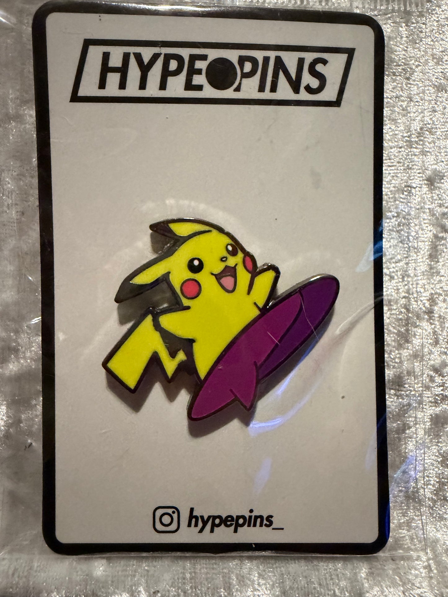 The **Surfing Pikachu Hard Enamel Pin**, a vibrant **Pokémon collectible** by Hype Pins, featuring Pikachu expertly riding a wave, perfect for any fan's collection.
